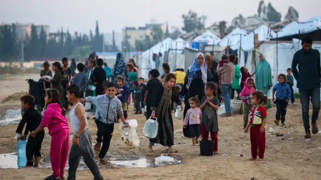 Des personnes remplissent leurs récipients d'eau au camp de Nuseirat pour Palestiniens déplacés, dans le centre de la bande de Gaza, le 4 décembre 2025.