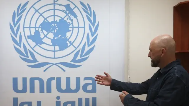 Le porte-parole de l'UNRWA, Jonathan Fowler, montre le logo de l'Agence dans son bureau du bureau régional de Cisjordanie à Jérusalem, le 29 octobre 2024.