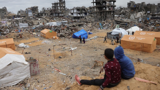 Des enfants palestiniens déplacés sont assis sur un monticule de sable surplombant des tentes installées au milieu de bâtiments détruits par l'armée d'occupation israélienne à Jabalia, dans le nord de la bande de Gaza, le 6 février 2025.