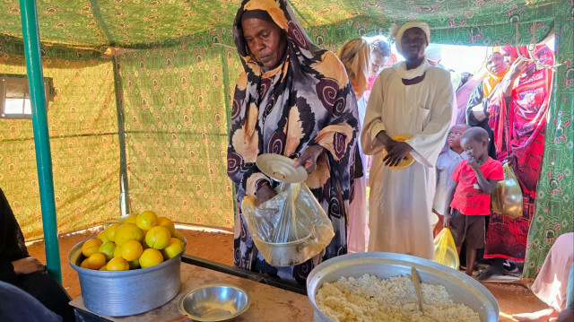 Une femme collecte de la nourriture dans un lieu mis en place par une organisation humanitaire locale pour donner des repas et des médicaments aux personnes déplacées par la guerre au Soudan, à Meroe dans l'État du Nord du pays, le 9 janvier 2025.