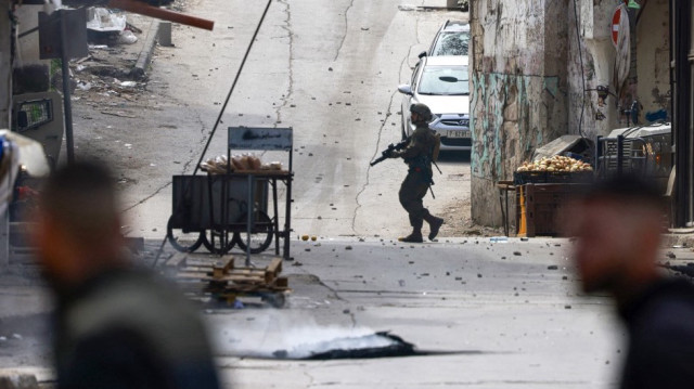Un soldat israélien traverse la route lors d'un raid militaire dans la vieille ville de Naplouse, en Cisjordanie occupée, le 16 février 2025.