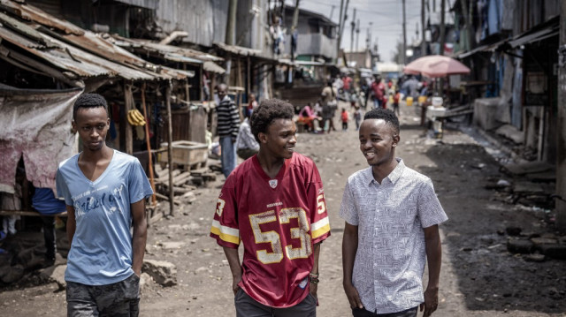 Geoffrey Mboya, 24 ans, (à droite) étudiant en travail social et développement communautaire à l'université Mount Kenya, activiste de premier plan, organisateur communautaire et défenseur du climat, marche avec quelques amis dans une rue du quartier informel de Mukuru à Nairobi, où il est né et a grandi. 