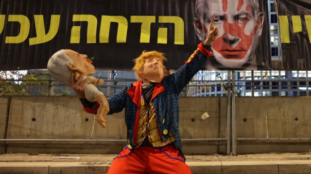 Un manifestant portant un masque de Donald Trump tient une poupée avec un masque du Premier ministre israélien Benjamin Netanyahu lors d'une manifestation à Tel Aviv, le 1er février 2025.