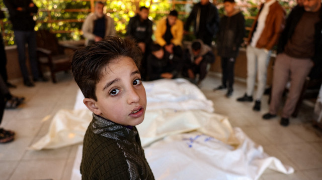 Un enfant se tient à côté des corps des quatre membres de la famille palestinienne al-Qadra (les parents et leurs deux enfants) tués lors d'une frappe israélienne qui a touché leur tente au nord de Khan Yunis dans le sud de la bande de Gaza, dans la cour de l'hôpital Nasser, le 18 janvier 2025, un jour avant la mise en œuvre prévue d'un accord de cessez-le-feu entre Israël et le Hamas.