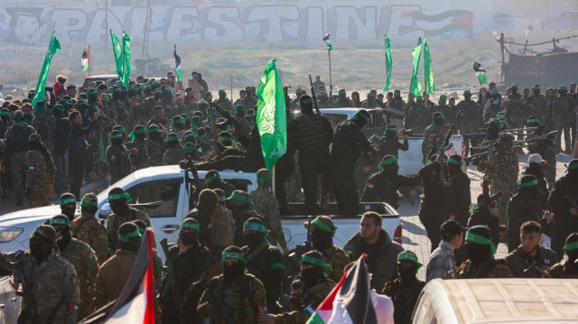 Des combattants du groupe militant palestinien Hamas sécurisent une zone avant de remettre un otage israélo-américain à une équipe de la Croix-Rouge dans la ville de Gaza, le 1er février 2025, dans le cadre du quatrième échange d'otages et de prisonniers.
