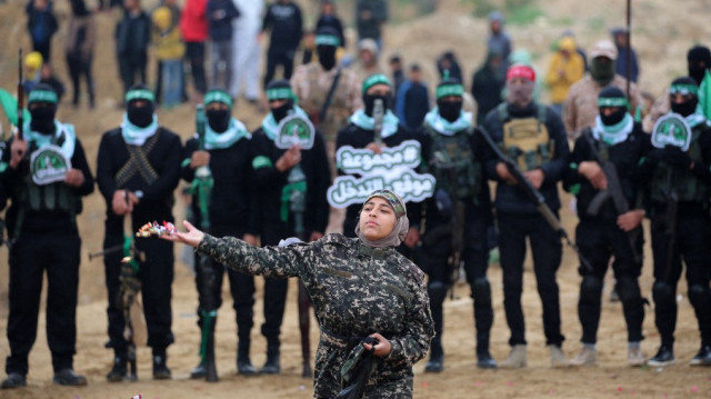 Une jeune fille palestinienne jette des fleurs alors que des militants du Hamas se rassemblent sur le site de la remise des corps de quatre otages israéliens à Khan Yunis, dans le sud de la bande de Gaza, le 20 février 2025.
