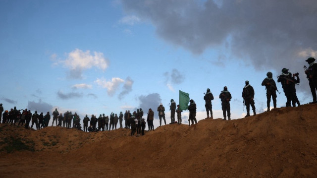 Des combattants du groupe militant palestinien Hamas sont au garde-à-vous avant la remise des corps de quatre otages israéliens à Khan Yunis, dans le sud de la bande de Gaza, le 20 février 2025.