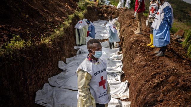 Un membre de la Croix-Rouge congolaise fait une pause tandis que d'autres portent des sacs mortuaires contenant des restes humains lors d'un enterrement de masse pour les victimes des affrontements dans l'est de la République démocratique du Congo au cimetière de Musigiko à Bukavu, le 20 février 2025.