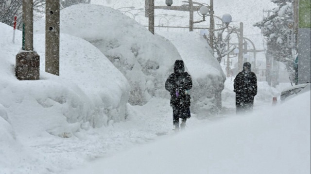 Des piétons passent devant de hautes congères dans une rue de la ville d'Aomori, dans le nord du Japon.