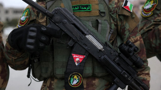 Un combattant palestinien du Hamas porte un fusil alors que des militants et des personnes se rassemblent sur le site de la remise d'otages israéliens au camp de réfugiés de Nuseirat, dans le centre de la bande de Gaza, dans le cadre de la septième libération d'otages et de prisonniers, le 22 février 2025.