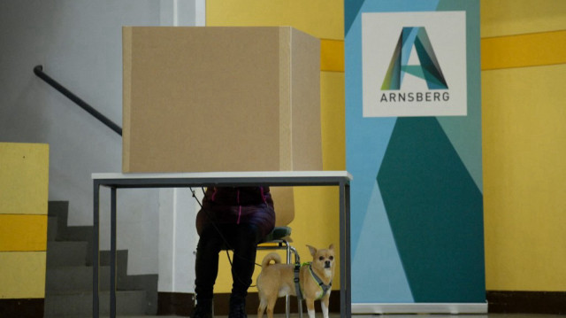 Une électrice avec un chien remplit son bulletin de vote dans un bureau de vote à Arnsberg, dans l'ouest de l'Allemagne, lors des élections générales du 23 février 2025.