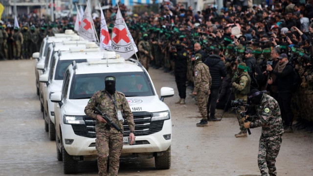 Un combattant palestinien du Hamas précède des véhicules de la Croix-Rouge internationale (CICR) à leur arrivée à Nuseirat, dans le centre de la bande de Gaza, pour accueillir trois otages israéliens dans le cadre du septième échange d'otages et de prisonniers, le 22 février 2025.