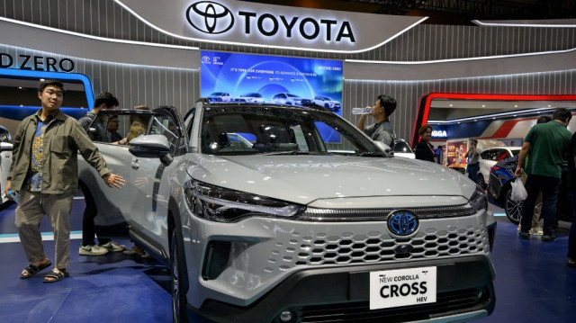 Des visiteurs examinent une nouvelle voiture hybride de type Corolla Cross de la marque Toyota.