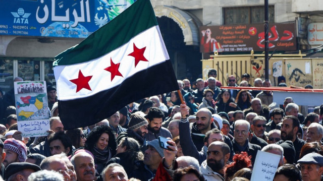 Des Syriens brandissent des pancartes alors qu'ils manifestent sur la place centrale Karama de la ville méridionale de Suwayda, le 25 février 2025.