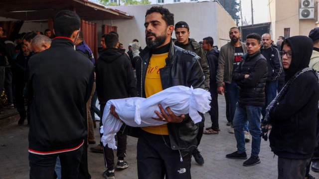 un homme porte le corps enveloppé d'un bébé tué lors de frappes israéliennes dans la ville de Gaza la nuit précédente, à l'hôpital Al-Ahli Arab.