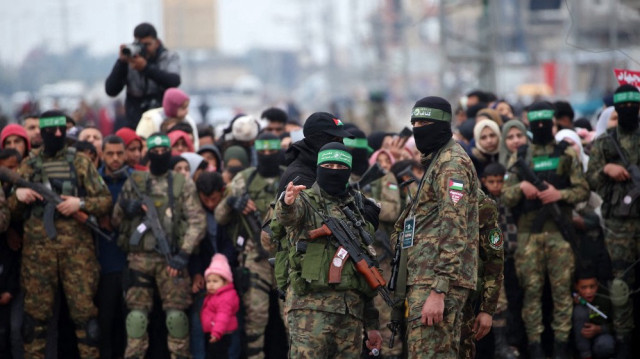 Des Palestiniens et des combattants du Hamas se rassemblent peu avant la libération de trois otages israéliens dans le cadre du septième échange d'otages et de prisonniers, à Nuseirat, dans le centre de la bande de Gaza, le 22 février 2025.