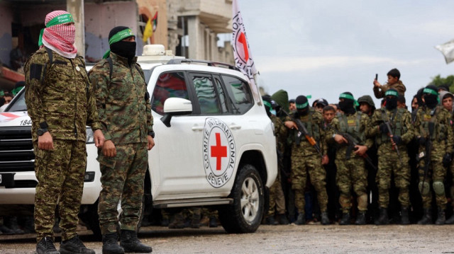 Des combattants du Hamas montent la garde alors qu'un véhicule de la Croix-Rouge internationale arrive sur le site de la remise de deux otages israéliens à Rafah, dans le sud de la bande de Gaza, dans le cadre de la septième libération d'otages et de prisonniers, le 22 février 2025.