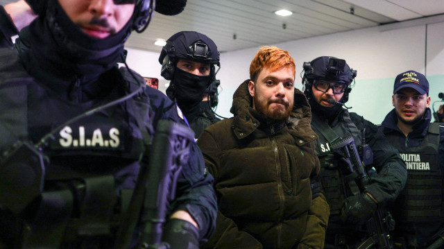 Le trafiquant de drogue français Mohamed Amra est escorté par des policiers à l'aéroport international Henri Coanda d'Otopeni, près de Bucarest, en Roumanie, le 25 février 2025, où il a été placé dans un avion pour être extradé vers la France.