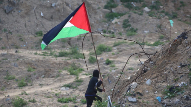 Un jeune Palestinien brandit le drapeau de la Palestine sur le site de la remise des corps de quatre otages israéliens à Khan Yunis, dans le sud de la bande de Gaza, le 20 février 2025.