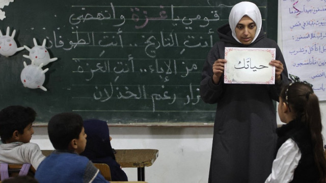 Un enseignant palestinien s'entretient avec un élève lors de la première journée de cours dans une école de la ville de Gaza, le 23 février 2025.