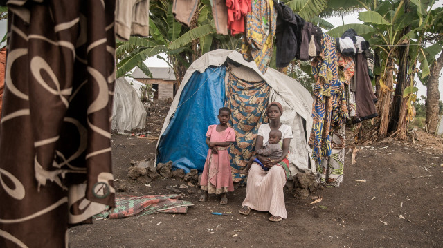 Une femme au visage couvert de sang, qui fait partie de ceux qui sont retournés dans leurs maisons pour constater qu'elles ont été détruites, pose pour une photo avec ses enfants à Sake, le 27 février 2025.