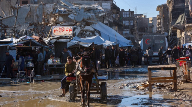 Un homme dirige une charrette tirée par un âne alors que des Palestiniens marchent sur un marché à Jabalia, dans le nord de la bande de Gaza, le 27 février 2025.