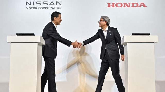 Makoto Uchida (à gauche), président et PDG du constructeur automobile japonais Nissan, et Toshihiro Mibe (à droite), directeur, président et représentant de la direction du constructeur automobile Honda, se serrant la main au début d'une conférence de presse à Tokyo, le 1er août 2024.