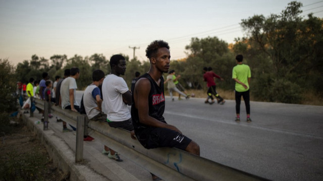 Un migrant somalien est assis sur une barrière de sécurité routière sur l'île de Lesbos, le 24 août 2020.