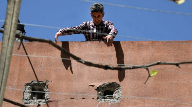Un homme se tient sur un toit au-dessus de trous d'éclats d'obus, dans le village de Hiror, près de la frontière turque, dans la région kurde autonome du nord de l'Irak.