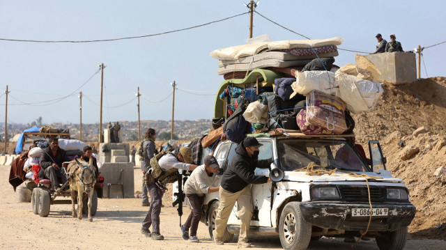 Des hommes aident à pousser un véhicule chargé alors que des Palestiniens déplacés traversent un point de contrôle tenu par la sécurité américaine et égyptienne dans le corridor de Netzarim, sur la route de Salah al-Din dans le centre de la bande de Gaza, le 29 janvier 2025. Des colonnes de Palestiniens transportant ce qu'ils pouvaient se sont dirigés vers le nord de la bande de Gaza le 29 janvier, pour la troisième journée consécutive, après qu'Israël a autorisé leur passage conformément au cessez-le-feu en vigueur.