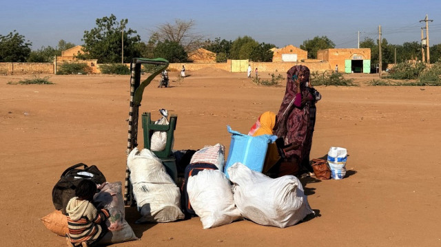 Un enfant et une femme attendent à côté de leurs affaires alors que les personnes déplacées par la guerre en cours au Soudan retournent à Wad Madani dans l'état de Jazira, le 6 février 2025.