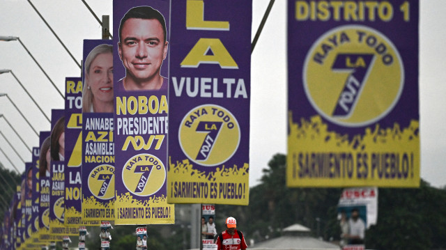 Un homme marche sur un pont décoré de propagande électorale pour le président équatorien et le candidat à la présidence Daniel Noboa à Guayaquil, Équateur, le 7 février 2025.