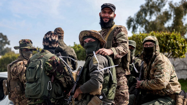 Les forces de sécurité loyales au gouvernement intérimaire syrien montent à l'arrière d'un véhicule circulant sur une route dans la ville de Lattaquié, à l'ouest de la Syrie, le 9 mars 2025.
