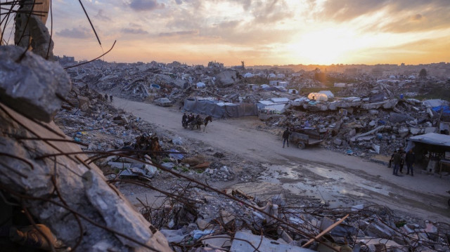 Des Palestiniens se promènent sur une charrette au milieu des décombres de bâtiments alors que le soleil se couche sur Beit Lahia, dans le nord de la bande de Gaza, le 4 mars 2025.