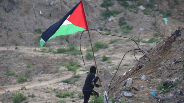 Un jeune Palestinien brandit le drapeau de la Palestine sur le site de la remise des corps de quatre otages israéliens à Khan Yunis, dans le sud de la bande de Gaza, le 20 février 2025.