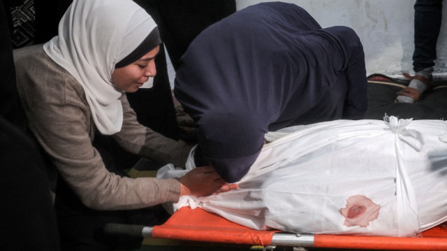 Des femmes se recueillent devant le corps d'une des victimes tuées lors d'un bombardement israélien dans le nord du camp de réfugiés palestiniens de Bureij, lors des funérailles dans le camp au centre de la bande de Gaza, le 11 mars 2025.