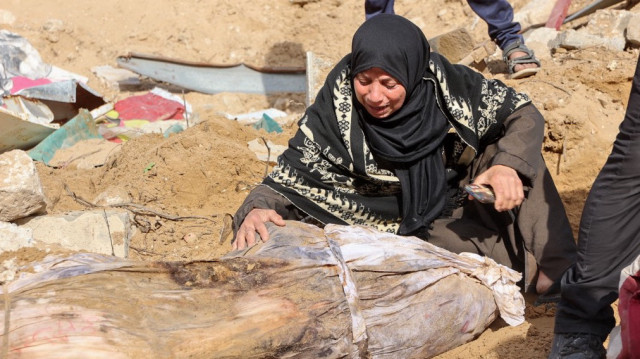 Une femme pleure sur un corps après que des agents de la défense civile palestinienne aient découvert des cadavres enterrés dans l'enceinte de l'hôpital Al-Shifa, dans la ville de Gaza, le 13 mars 2025.