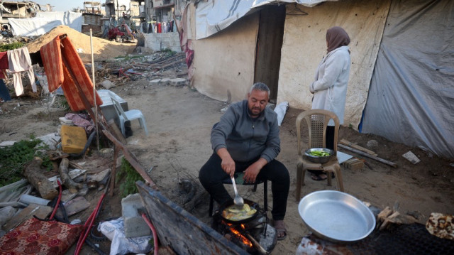 Un Palestinien prépare le repas de l'iftar à l'extérieur de son abri dans le camp de réfugiés palestiniens de Bureij, dans le centre de la bande de Gaza, le 11 mars 2025, pendant le mois de jeûne musulman du Ramadan.