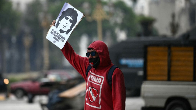 Un manifestant tient une pancarte représentant feu le footballeur argentin Diego Maradona lors d'une manifestation à Buenos Aires, le 12 mars 2025.