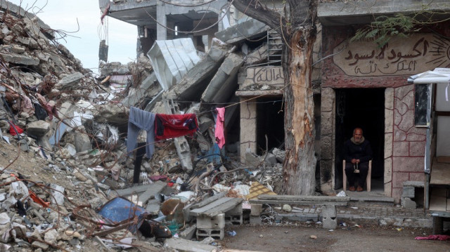 Un Palestinien est assis à la porte d'un bâtiment endommagé par la guerre.