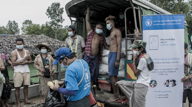Des personnes attendent de recevoir des sacs de riz distribués par le Programme alimentaire mondial (PAM) dans le cadre des efforts d'aide alimentaire visant à soutenir les résidents vivant dans des communautés pauvres à la périphérie de Yangon.