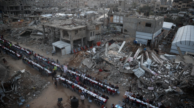 Cette photographie aérienne montre des Palestiniens rassemblés pour un repas communautaire de rupture du jeûne, l'iftar, au milieu de la dévastation du camp de réfugiés de Nuseirat, dans le centre de la bande de Gaza, pendant le mois de jeûne musulman du Ramadan, le 14 mars 2025.