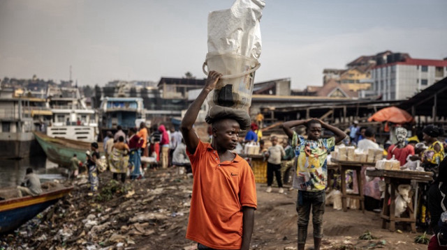 Un vendeur ambulant porte des marchandises sur sa tête tout en cherchant des clients à un quai de pirogue sur les rives du lac Kivu à Bukavu le 21 février 2025, alors qu'environ 42 000 personnes ont fui le conflit qui fait rage dans l'est de la République démocratique du Congo et sont passées au Burundi au cours des deux dernières semaines, ont déclaré les Nations Unies aujourd'hui.