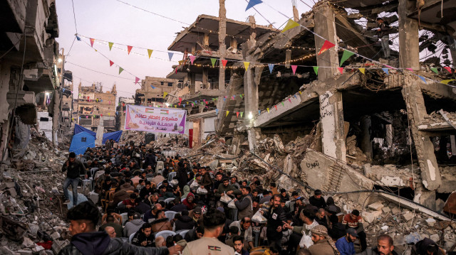 Des personnes se rassemblent pour l'iftar, ou repas de rupture du jeûne, le premier jour du mois de jeûne musulman du Ramadan à Jabalia, dans le nord de la bande de Gaza, le 1er mars 2025, près des décombres de bâtiments effondrés qui ont été détruits pendant la guerre entre Israël et le Hamas, dans le cadre de la trêve en cours.