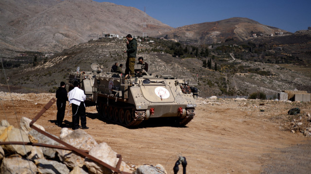 Des juifs ultra-orthodoxes parlent à des soldats montés sur un véhicule blindé de transport de troupes dans la zone tampon qui sépare le plateau du Golan annexé par Israël et la Syrie, près du village druze de Majdal Shams, le 27 février 2025. À la suite du renversement du président syrien en décembre 2024, Israël a mené une vague de centaines de frappes contre des positions précédemment tenues par son armée, tout en envoyant des troupes dans une zone tampon contrôlée par les Nations unies qui sépare les forces israéliennes et syriennes sur les hauteurs stratégiques du Golan depuis 1974.