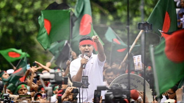 Un étudiant crie des slogans tandis que des manifestants brandissent le drapeau national du Bangladesh lors de la Marche des martyrs, un rassemblement organisé par les étudiants contre la discrimination pour marquer le premier mois de l'éviction de l'ancien Premier ministre Sheikh Hasina, à Dhaka, le 5 septembre 2024.