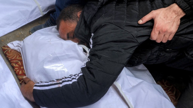 Une personne en deuil fait ses adieux au corps d'une des victimes de la famille palestinienne Abu al-Rous qui ont été tuées lorsque leur maison a été touchée par un bombardement israélien, lors des funérailles au camp de Bureij pour les réfugiés palestiniens dans le centre de la bande de Gaza, le 25 mars 2025.