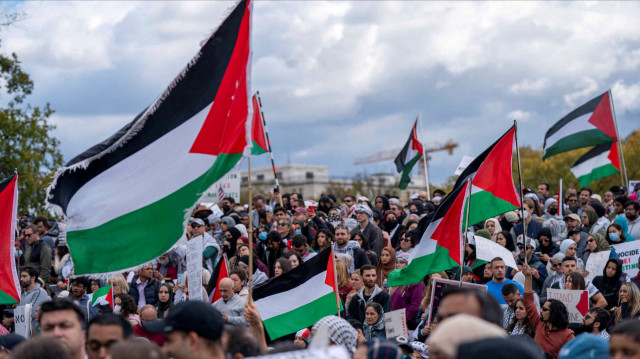 Люди поднимают флаги и плакаты во время митинга в Вашингтоне, организованного организацией "American Muslims for Palestine" с призывом к прекращению огня в Газе, 21 октября 2023 года.