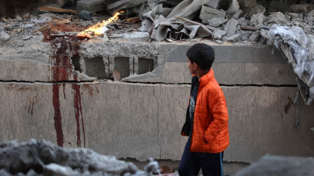 Un garçon passe devant des taches de sang sur le site d'une frappe israélienne sur une maison à Khan Yunis, dans le sud de la bande de Gaza, le 8 janvier 2025.