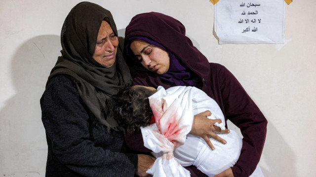 La mère (à droite) de la jeune victime Ibtissam Elyan berce le corps de sa fille qui a été tuée avec d'autres victimes de la famille Elyan lors d'un bombardement israélien sur leur maison à Beit Lahia dans le nord de la bande de Gaza, à l'hôpital indonésien de Beit Lahia le 25 mars 2025. Israël, qui s'est engagé à détruire le groupe militant palestinien Hamas, a repris le 18 mars d'intenses bombardements sur Gaza et a redéployé des troupes au sol, rompant ainsi une trêve qui tenait à peu près depuis le 19 janvier.